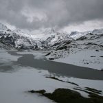 Bleak alpine landscape at Bachalpsee in the Swiss Alps, with the frozen lake in the foreground and snow-covered mountains under heavy cloud.